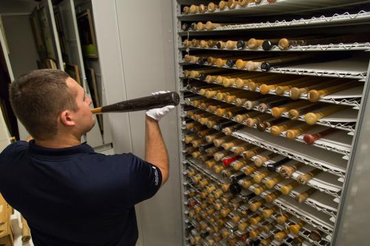 A Hall of Fame staff member placing a bat in the collection storage vault