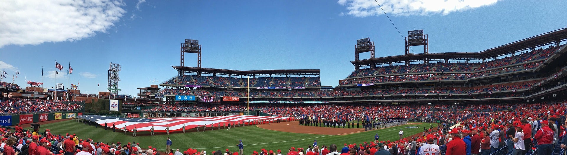 View of the field at Citizens Bank Park from the left field line. There is a large American Flag spread across the outfield during a pre-game ceremony.