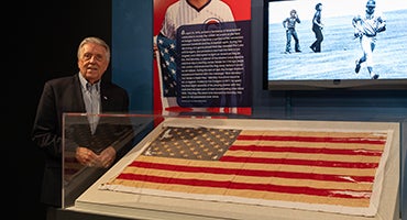 Rick Monday stands next to United States flag