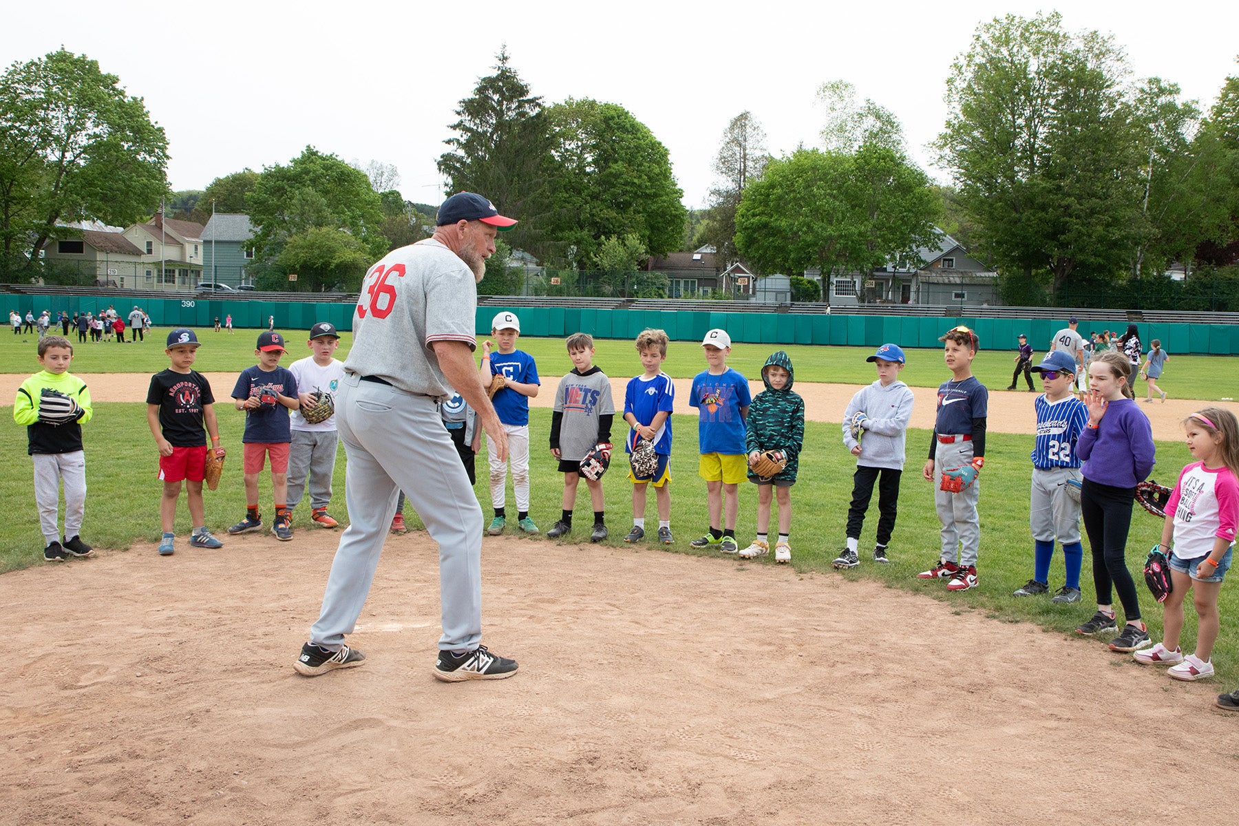 Mark Dewey instructs group of youth players on pitching mound