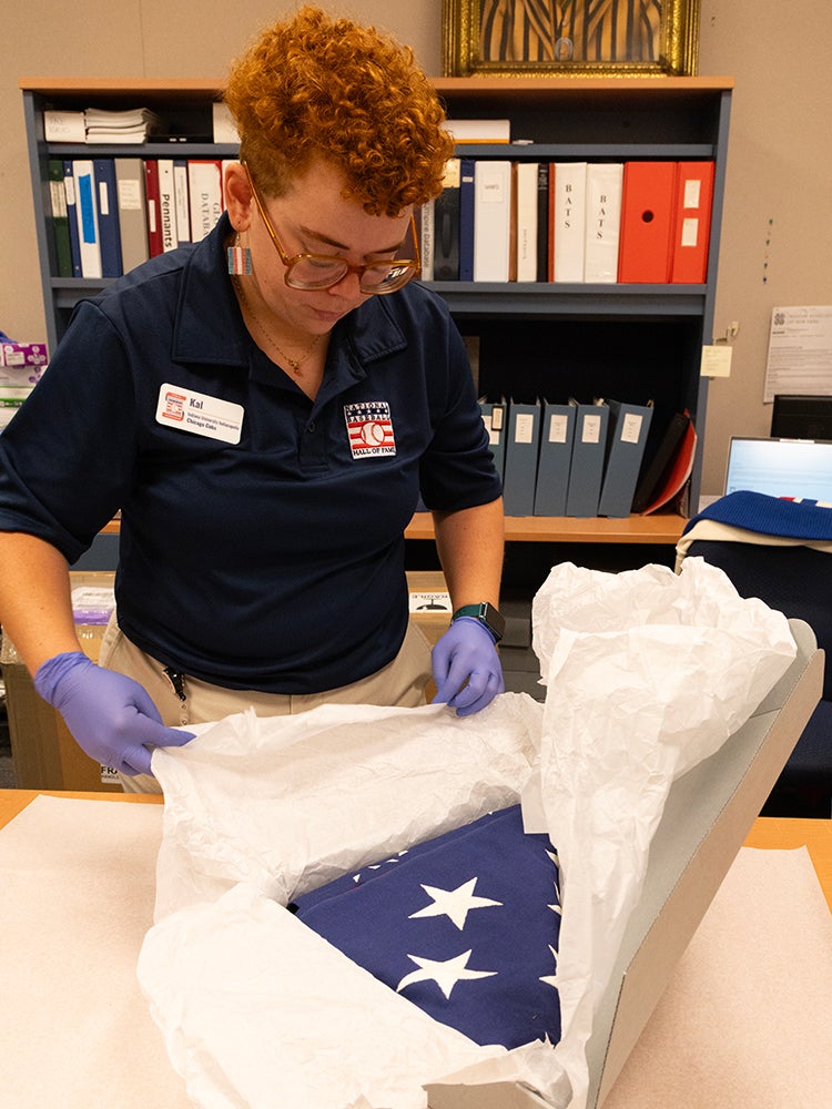 Museum professional unwraps acid-free paper inside box containing American flag