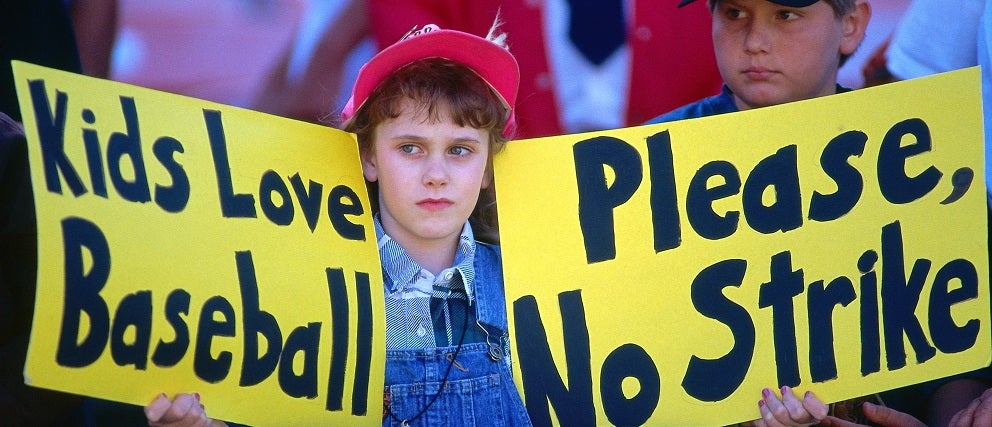 ​    ​Baseball fan Erin States holds up signs that read "Kids love baseball" and "Please, no strike" before a game between the Seattle Mariners and Oakland Athletics at the Oakland Coliseum in Oakland, California on August 12, 1994. This was the last game played before the strike was called.