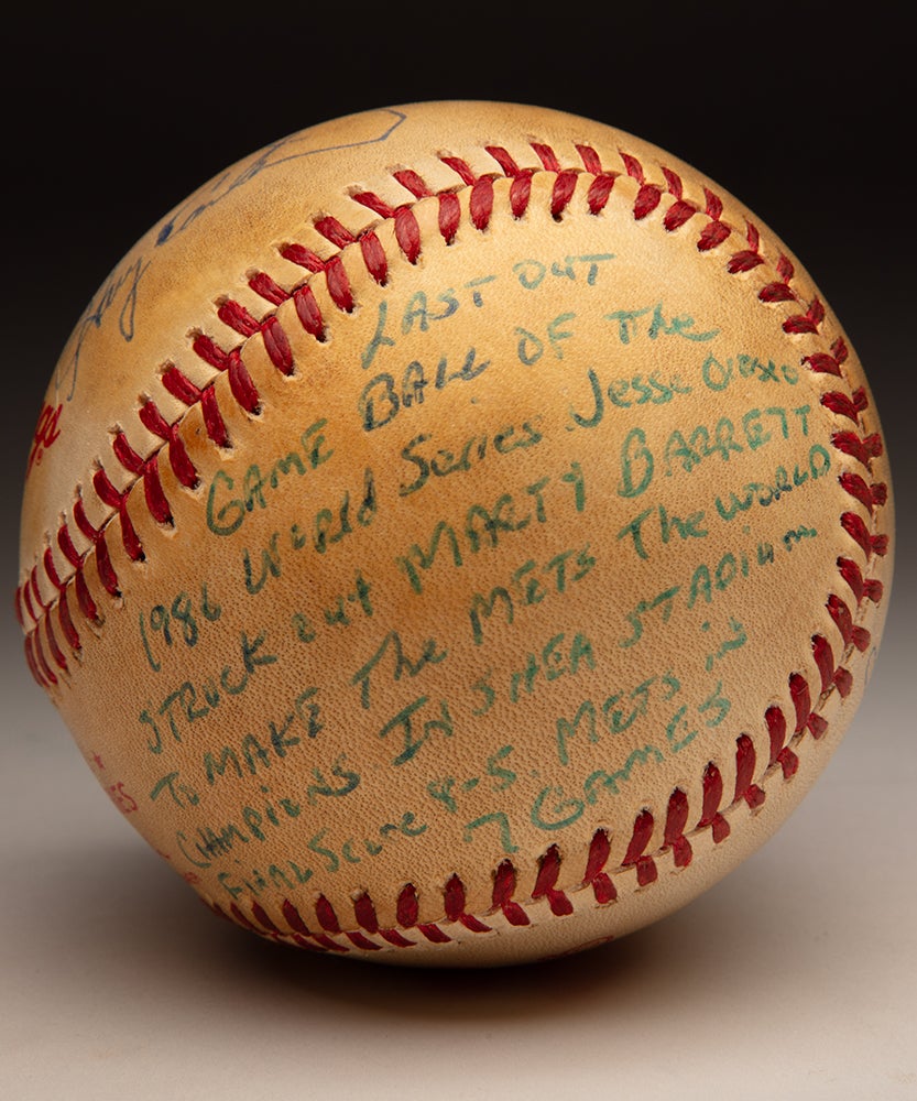 Inscription on baseball reads 'Last out game ball of the 1986 World Series - Jesse Orosco struck out Marty Barrett to make the Mets World Series champions in Shea Stadium - final score 8-5 - Mets in 7 games"