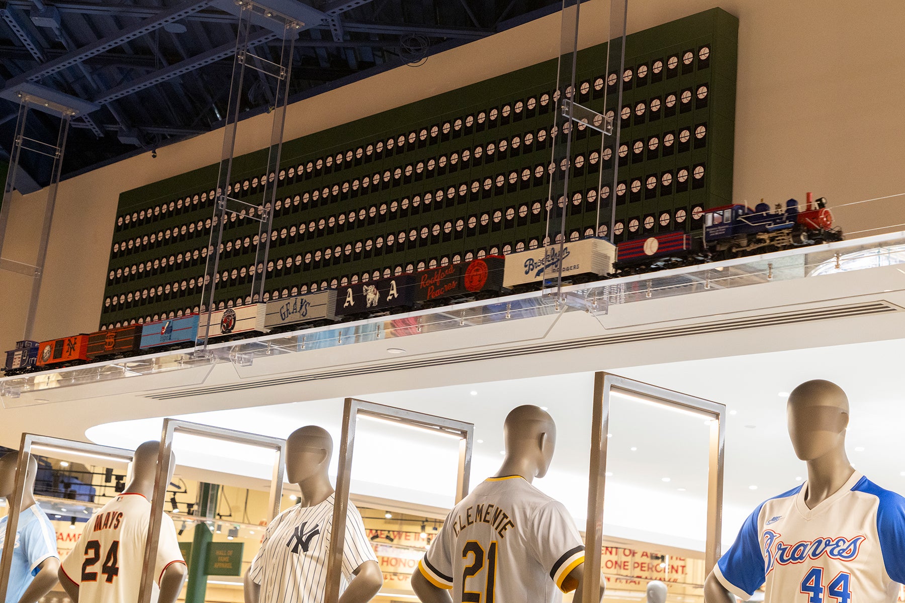Model train passes in front of split-flap display board