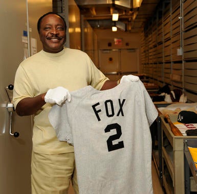 Joe Morgan holds a jersey of one of his heroes, Hall of Fame second baseman Nellie Fox, during a tour of the Museum archives. (Milo Stewart Jr./National Baseball Hall of Fame and Museum)